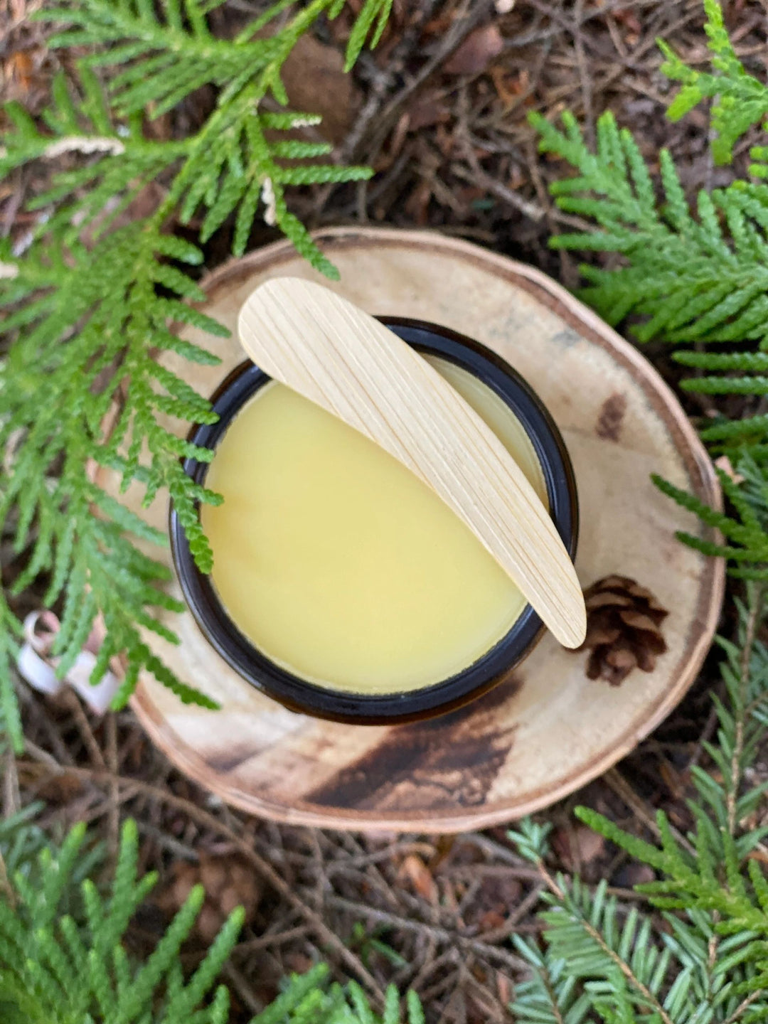 Balm in a amber jar  with a bamboo applicator on a natural background