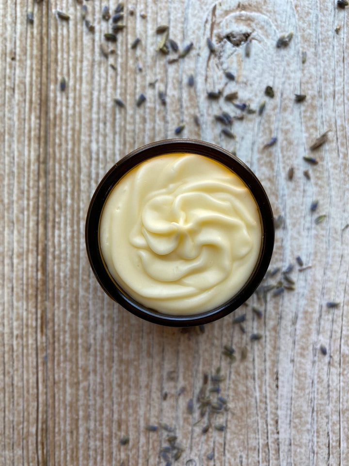 Calendula Tallow Balm in a amber jar on a wooden surface with dried lavender and chamomile buds.