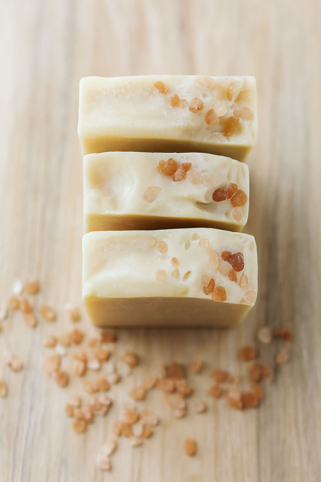 Stack of three soap bars with Himalayan salt specks on a wooden surface