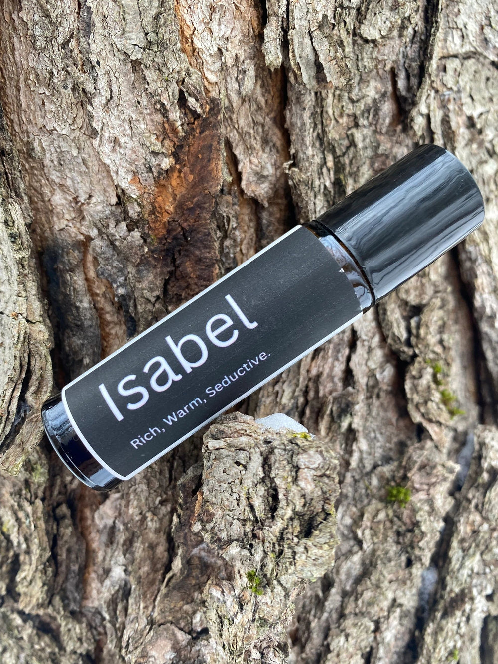 Perfume bottle labeled 'Isabel' against a tree bark background
