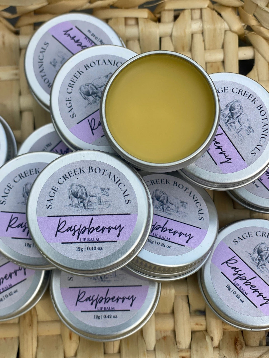 Sage Creek Botanicals Raspberry lip balm tins on a woven surface