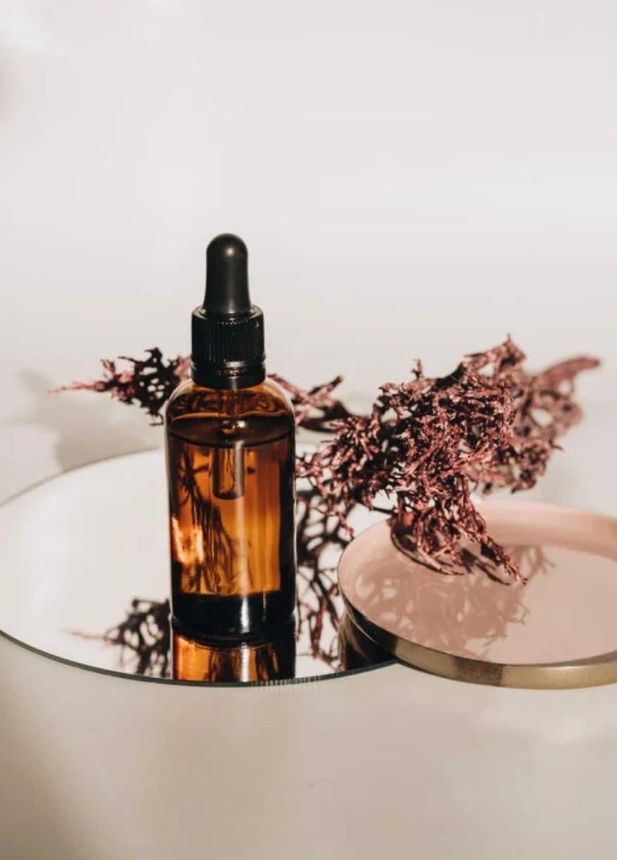 amber glass dropper bottle of Serum 0.5 on a white surface with dried flowers.